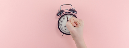 Creative banner morning time emotions concept top view of woman hand holding black vintage alarm...