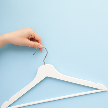 Creative top view flat lay white wooden hangers isolated pastel blue background with copy space minimalism style. Template fashion feminine blog social media sale store promo design shopping conceptの写真素材