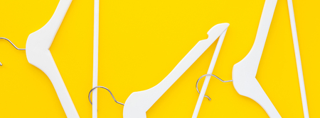 Creative top view flat lay white wooden hangers isolated bold yellow background with copy space minimalism style. Template fashion feminine blog social media sale store promo design shopping conceptの写真素材
