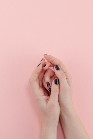 Stylish trendy female black manicure. Beautiful young woman's hands on millennial pink pastel background. Beauty and SPA concept. Template for feminine blog social mediaの写真素材
