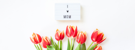 Creative flat lay top view Mothers Day greeting card with red tulips spring flowers on white background. Celebration Postcard templateの写真素材