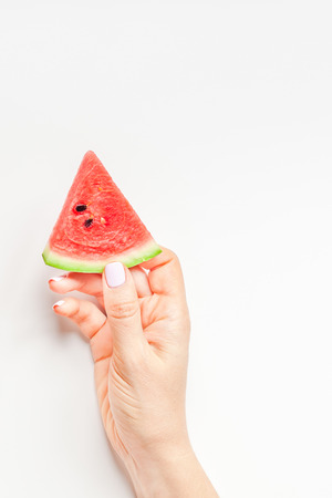 Creative scandinavian style flat lay top view of fresh watermelon slices in woman hands on white table background copy space. Minimal summer fruits creative for blog or recipe bookの写真素材