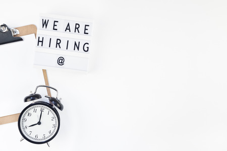 Creative top view flat lay of desk with we are hiring text on lightbox with copy space on white background in minimal style. Concept of new job, hiring recruitment process, new team members screeningの写真素材