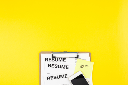 Creative top view flat lay of desk with resume documents copy space on bold yellow background in minimal style. Concept of new job, hiring recruitment process, new team members screeningの写真素材