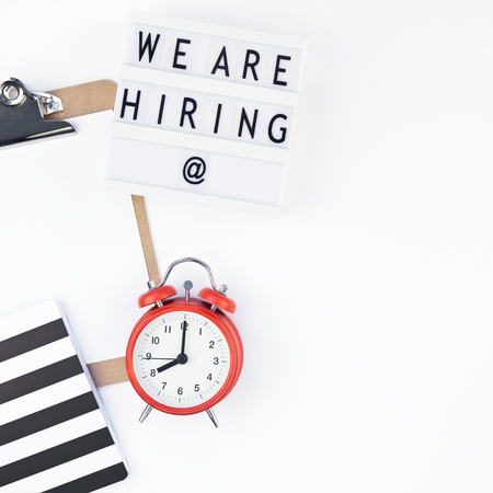 Creative top view flat lay of desk with we are hiring text on lightbox with copy space on white background in minimal style. Concept of new job, hiring recruitment process, new team members screeningの写真素材