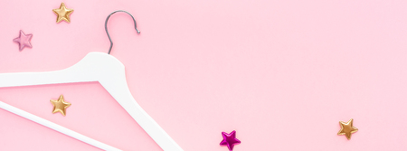 Creative top view flat lay white wooden hangers pastel millennial pink background with copy space minimalism style. Template fashion feminine blog social media sale store promo design shopping conceptの写真素材