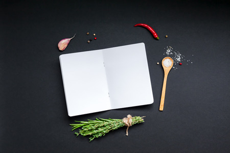 Flat lay overhead view blank notebook pages mockup text space invitation card on black background with greens herbs and spices. Menu or recipe book or food blog design with cooking ingredientsの写真素材