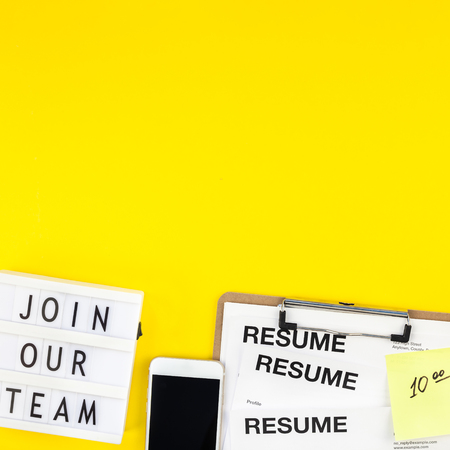 Creative top view flat lay of desk with join our team text on lightbox copy space on bold yellow background in minimal style. Concept of new job, hiring recruitment process, new team members screeningの写真素材