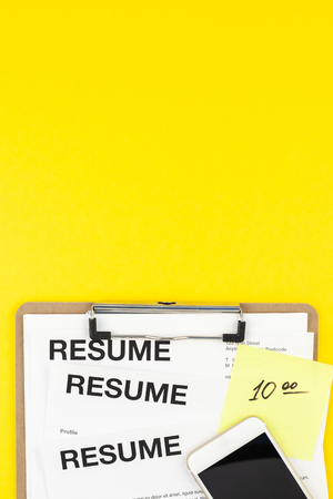 Creative top view flat lay of desk with resume documents copy space on bold yellow background in minimal style. Concept of new job, hiring recruitment process, new team members screeningの写真素材