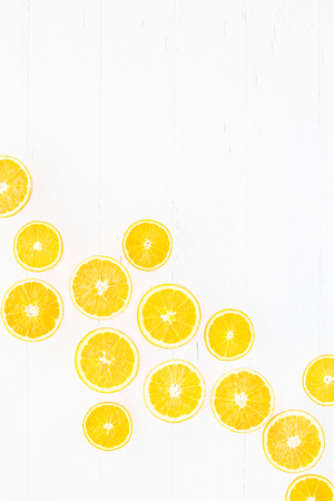 Creative scandinavian style flat lay top view of fresh orange fruit slices on white wooden table background with copy space. Minimal summer fresh citrus pattern for blog or recipe bookの写真素材