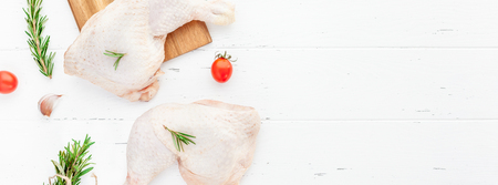 Creative Top view flat lay of fresh raw chicken legs with rosemary herbs garlic tomatoes on white wooden background with copy space. Food preparation recipe cooking conceptの写真素材