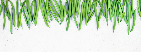 Creative scandinavian style flat lay top view of fresh green beans on white concrete table background copy space. Minimal house cooking concept template for blog or recipe bookの写真素材