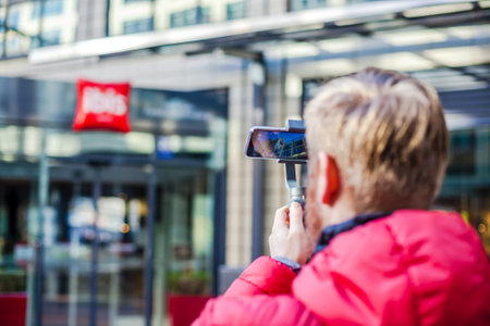 GERMANY, MUNICH - DECEMBER 26, 2018: Man blogger shooting video on smartphone IPhoneXS using an...