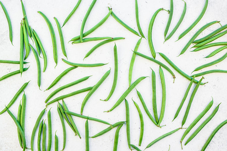 Creative scandinavian style flat lay top view of fresh green beans on white concrete table...