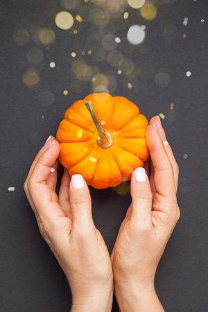 Creative Top view flat lay autumn composition. Concept orange pumpkin female hands black paper background copy space minimalism Template fall harvest thanksgiving halloween anniversary invitation cardの写真素材