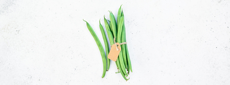 Creative scandinavian style flat lay top view of fresh green beans on white concrete table...