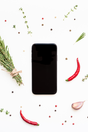 Flat lay overhead view smartphone mockup blank text space on white background with greens herbs and spices. Menu design food blog recipe cookbook or delivery app with cooking ingredientsの写真素材