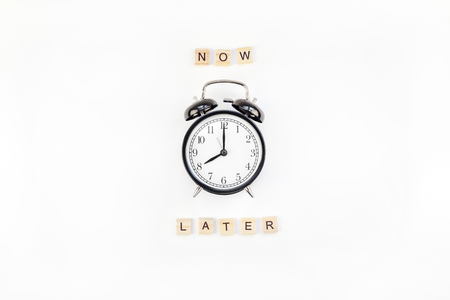 Creative top view flat lay of alarm clock with messages about delay or starting doing task copy space white background minimal style. Concept of procrastination, time management in business and lifeの写真素材