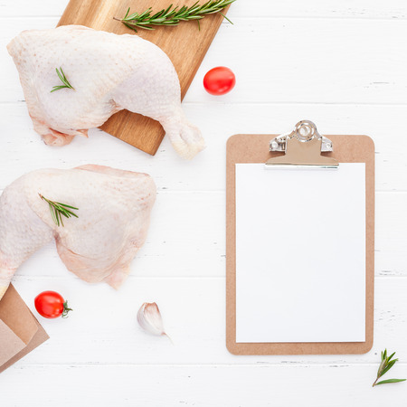 Creative Top view flat lay of fresh raw chicken legs with rosemary herbs garlic tomatoes on white wooden background with copy space. Food preparation recipe cooking conceptの写真素材