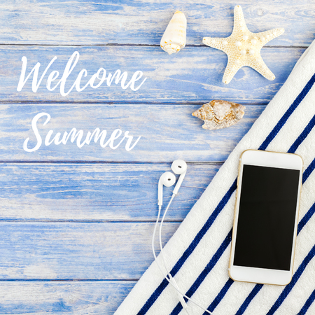 Square Creative flat lay concept of summer travel vacations. Top view of beach towel smartphone seashells starfish on pastel blue wooden planks background with Welcome summer textの写真素材