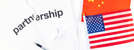 Creative top view flat lay of China and USA flag and broken partnership contract with pen and copy space on white background in minimal style. Concept of trade war between USA and Chinaの写真素材