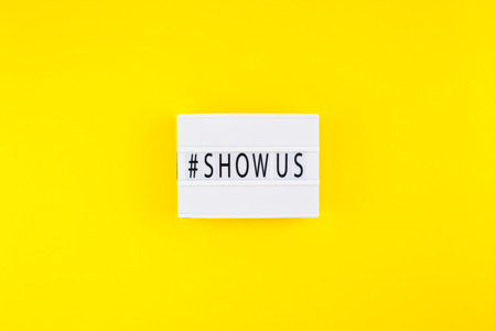 Creative top view flat lay of lightbox with hashtag Show Us message bold yellow background minimal...