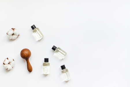 Massage and body care treatment concept with copy space. Creative top view flat lay composition with oil bottles, wooden eastern touch pressure points massage tool, cotton flowers on white backgroundの写真素材