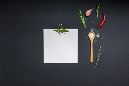 Flat lay overhead view blank recipe paper page with clip mockup text space invitation card on black background with greens herbs and spices. Menu recipe book food blog design with cooking ingredientsの写真素材