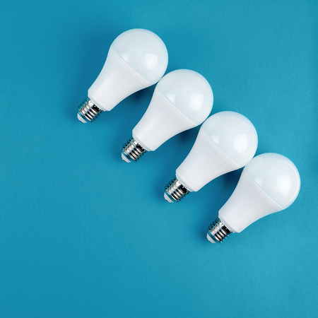 Energy-saving and eco-friendly life in conceptual frame pattern. Creative top view flat lay of LED light bulbs composition with copy space on blue background in minimal style.の写真素材