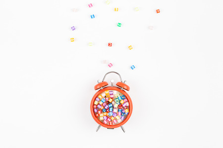Creative flat lay back to school education concept with alarm clock and multicolor letters isolated on white background with copy space, template for text or designの写真素材