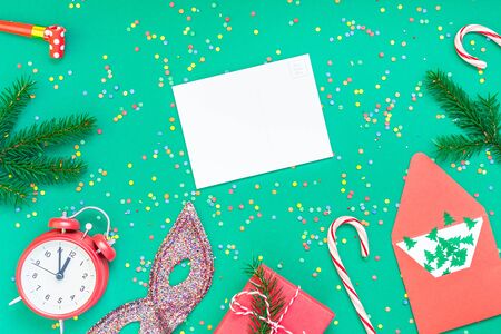 New Year or Christmas mock up flat lay top view with red alarm clock twelve midnight fir tree branch Xmas holiday celebration green paper bright colorful confetti background. Mockup text design 2020の写真素材