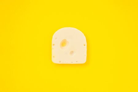Cheese piece in Creative conceptual top view flat lay composition with copy space isolated on bold yellow background in minimal styleの写真素材