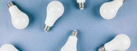Energy-saving and eco-friendly life in conceptual frame pattern. Creative top view flat lay of LED light bulbs composition with copy space on blue background in minimal style.の写真素材