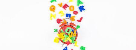 Creative flat lay back to school education concept with alarm clock and multicolor letters isolated...