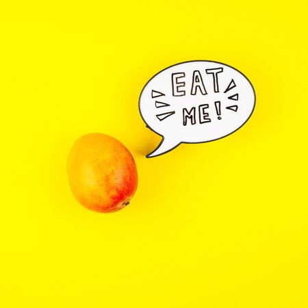 Mango fruit in creative conceptual top view flat lay composition with lightbox bubble with Eat me handwritten slogan isolated on bold color background in minimal style with copy space. Pop art posterの写真素材