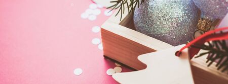 New Year Christmas Xmas holiday celebration composition pearl decorative toy balls wooden box fir branch sparkles confetti pink paper background copy space Template text design Long wide bannerの写真素材