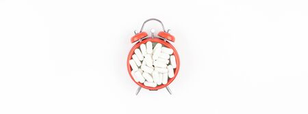 Nutritional supplement white pills on red alarm clock face isolated on white background with copy...