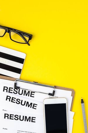 Creative top view flat lay of desk with resume documents copy space on bold yellow background in minimal style. Concept of new job, hiring recruitment process, new team members screeningの写真素材