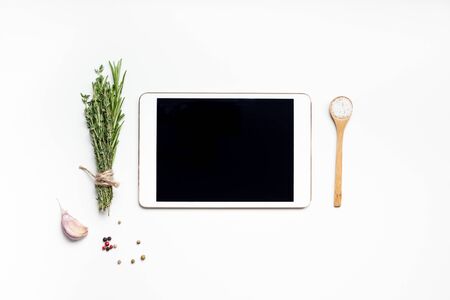 Flat lay overhead view tablet PC gadget mockup blank text space on white background with greens herbs and spices. Menu design food blog recipe cookbook or delivery app with cooking ingredientsの写真素材