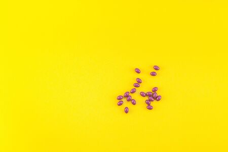 Nutritional supplement purple pills isolated on bold yellow background with copy space. Template for feminine beauty blog social media. Female healthcare conceptの写真素材