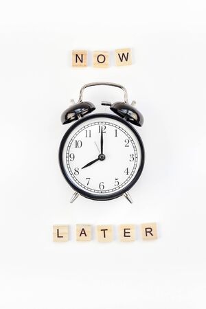 Creative top view flat lay of alarm clock with messages about delay or starting doing task copy space white background minimal style. Concept of procrastination, time management in business and lifeの写真素材