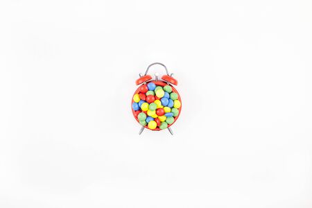 Birthday party invitation card template. Red alarm clock with multicolor candies on white...