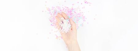 Pearl pastel confetti sparkles with woman hand on white background. Creative conceptual top view flat lay backdrop for your blog, text or designの写真素材