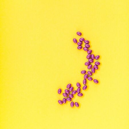 Nutritional supplement purple pills isolated on bold yellow background with copy space. Template for...