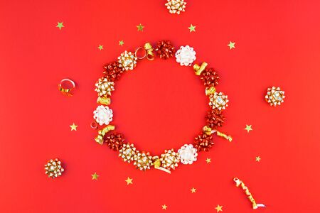 Christmas composition. New Year or Christmas pattern flat lay top view Xmas holiday celebration decorative golden round wreath frame on red background with copy space. Template of greeting cardの写真素材
