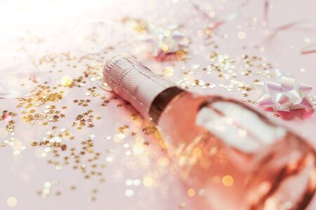 Christmas or New Year composition with bottles of rose champagne and golden shiny sparkle star confetti on pastel pink background, side view. Party Celebration creative conceptの写真素材