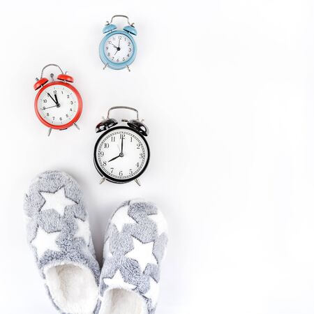 Sleep. Soft fluffy slippers and set of alarm clocks isolated on white background. Creative conceptual top view flat lay in minimal style. Rest, good night, insomnia, relaxation, tired, hygge conceptの写真素材