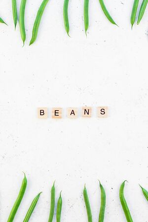 Creative scandinavian style flat lay top view of fresh green beans and text on white concrete table...