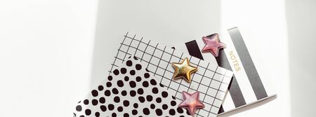 Desktop feminine composition with patterned notepads, golden stars and deer clips on white table with sun light and shadows. Top view flat lay concept for bloggerの写真素材