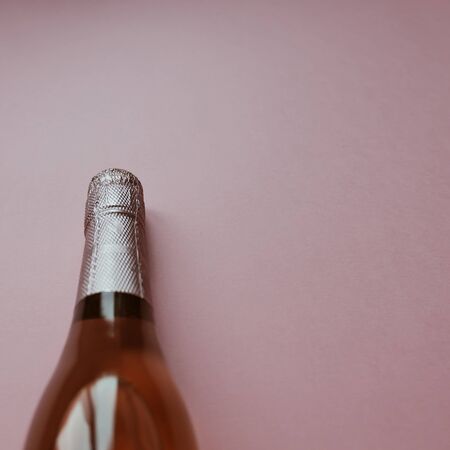 Bottle of rose champagne wine in minimal composition on pink background with copy space. Natural light. Template for tasting, degustation invitation card. Top viewの写真素材